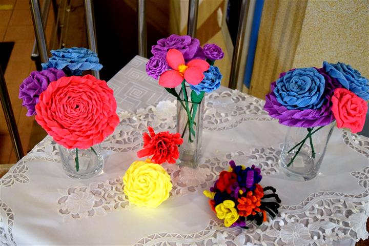 Wystawa kwiatów wykonanych z bibuły oraz patyczków kreatywnych. Kwiaty w kolorach czerwonym, żółtym, niebieskim, różowym